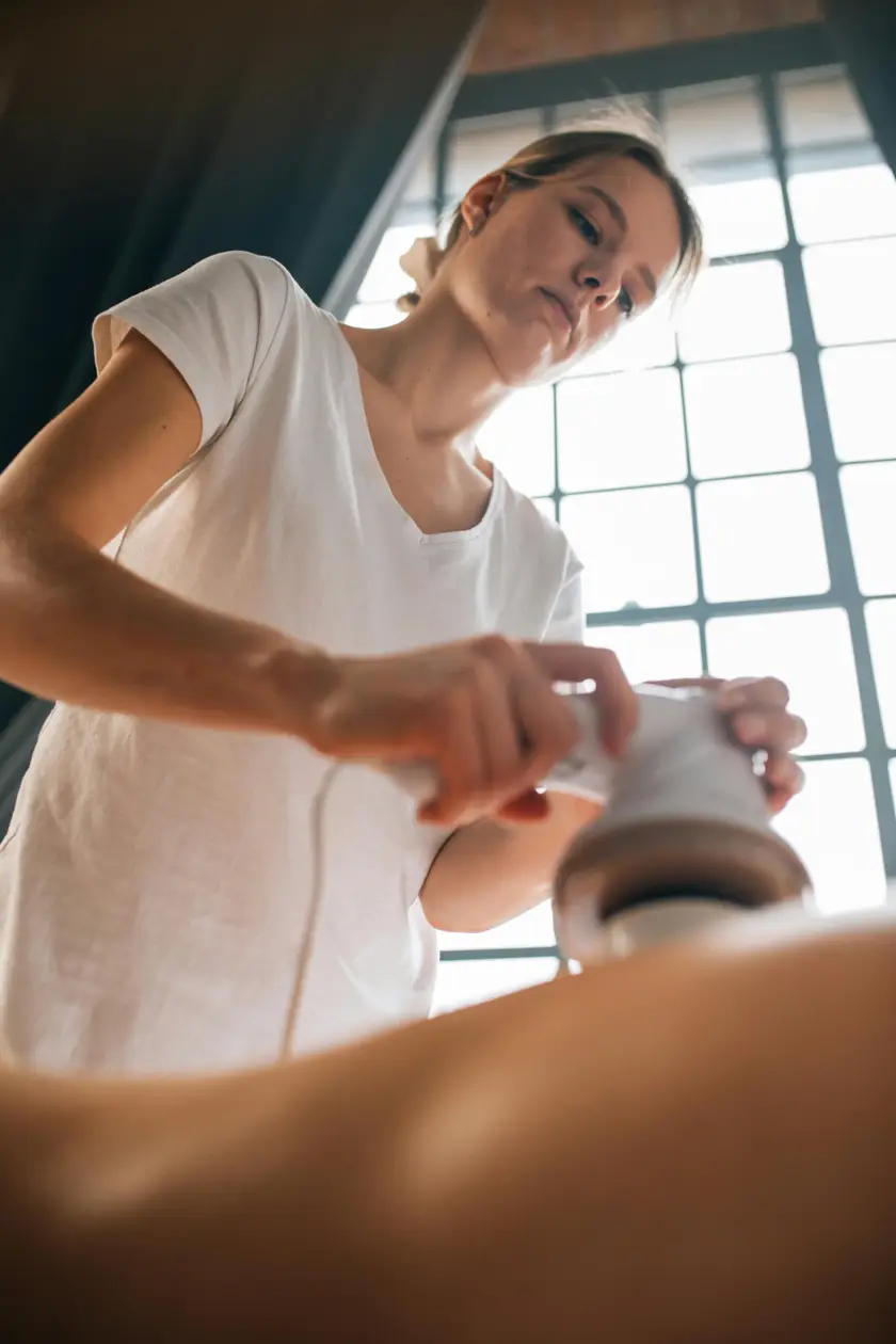 Praticienne au travail en cabine, dans la lumière naturelle — la formation est ancrée dans la pratique.