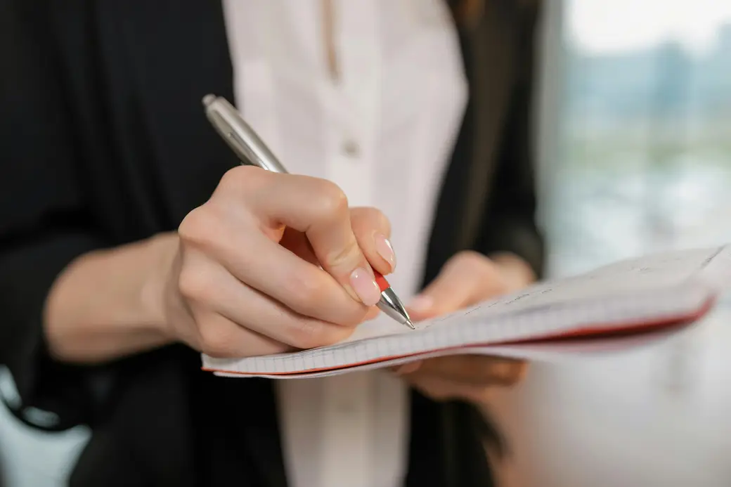Mains qui prennent des notes dans un carnet — l'observation et l'analyse au cœur de l'audit.